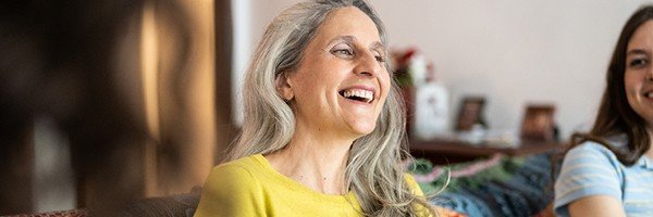 Smiling woman sits with family chatting after receiving her AGM pack