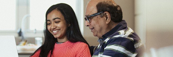 Smiling grandfather and granddaughter browse the Marsden news section together in their Guernsey home. 