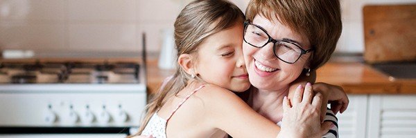 Woman hugs girl in the kitchen of her home insured by Marsden Building Society and Uinsure