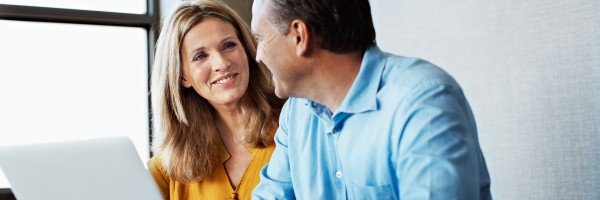 Couple sat at a laptop and smiling