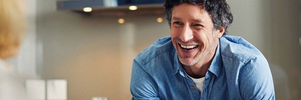 Man smiles at partner over breakfast after taking out an Expat Buy to Let Mortgage with the Marsden Building Society