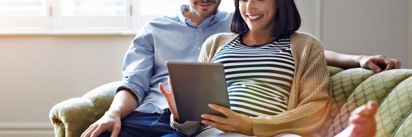 Couple sat on sofa looking at a tablet