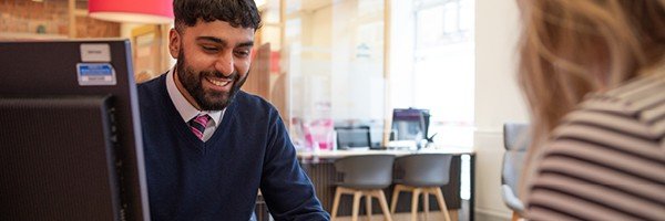 Smiling branch colleague helps a member to top up their ISA in branch