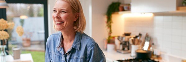 Woman smiles in her kitchen after topping up her online ISA with the Marsden