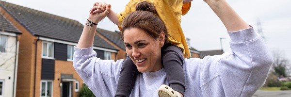 Mum takes a walk with her toddler on her shoulders, reassured that she's building her savings with a Workplace Savings scheme