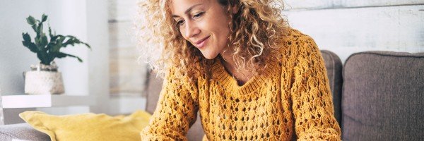 Mortgage Jargon: Woman sat on a sofa looking at a laptop 