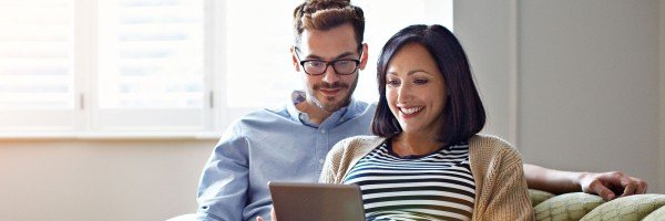 Couple sat on sofa looking at a tablet