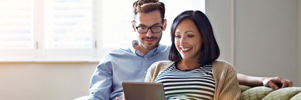 Couple sat on sofa looking at a tablet