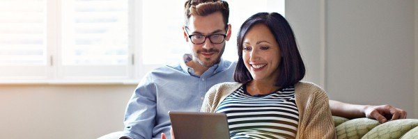 Couple sat on sofa looking at a tablet