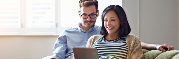 Couple sat on sofa looking at a tablet
