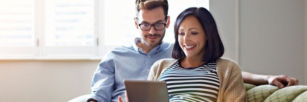 Couple sat on sofa looking at a tablet