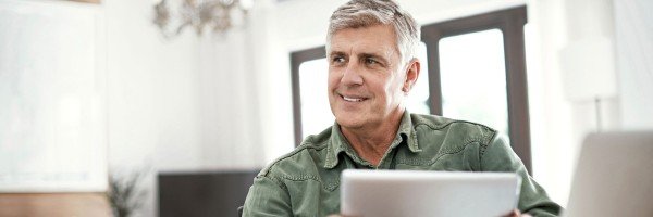 Smiling mature man contacts SPF via email using his tablet.