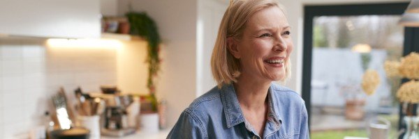 Mature woman smiles in her kitchen after applying for a mortgage with the Marsden in Guernsey.