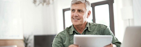 Smiling mature man contacts SPF via email using his tablet.