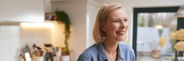 Mature woman smiles in her kitchen after applying for a mortgage with the Marsden in Guernsey.