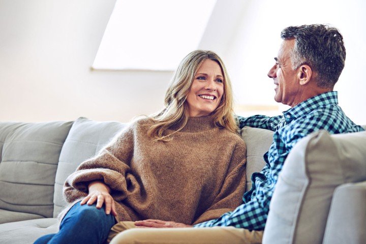 Happy couple sit on sofa after discussing Expat Residential mortgages with Marsden Building Society in Guernsey.