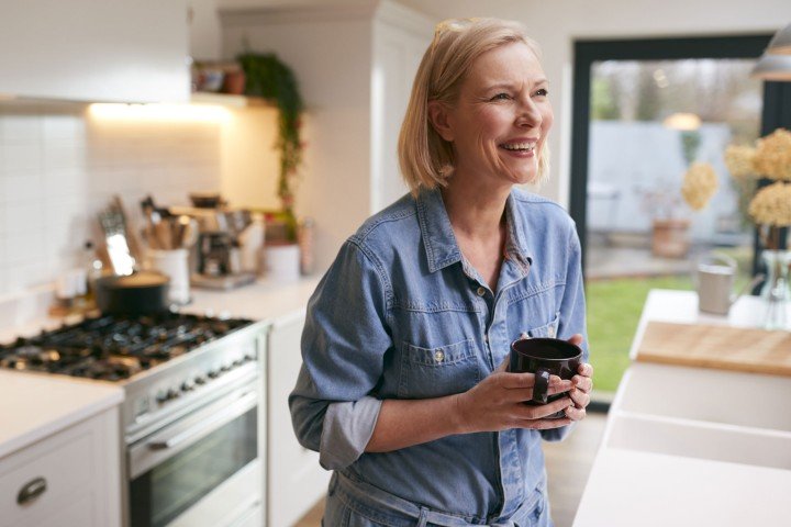 Mature woman smiles in her kitchen after applying for a mortgage with the Marsden in Guernsey.
