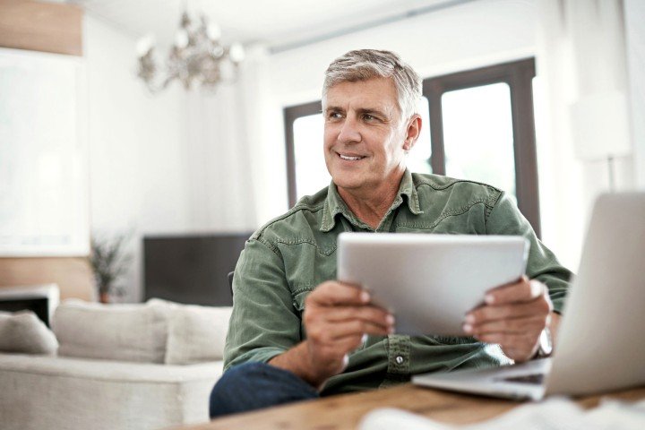 Smiling mature man contacts SPF via email using his tablet.