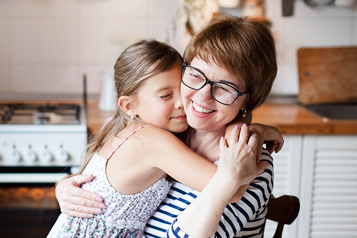 Smiling mother and young daughter hug each other in their new home after taking out insurance with the Marsden.