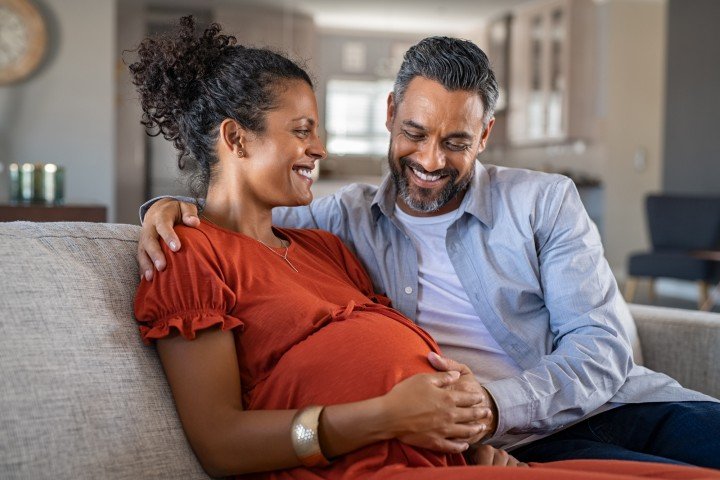 Pregnant couple sit together in their home after agreeing additional borrowing on their mortgage with Marsden Building Society