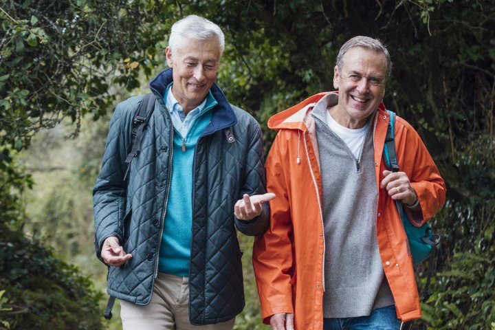 Two mature friends smiling and discussing the benefits of opening a cash ISA with the Marsden Building Society.