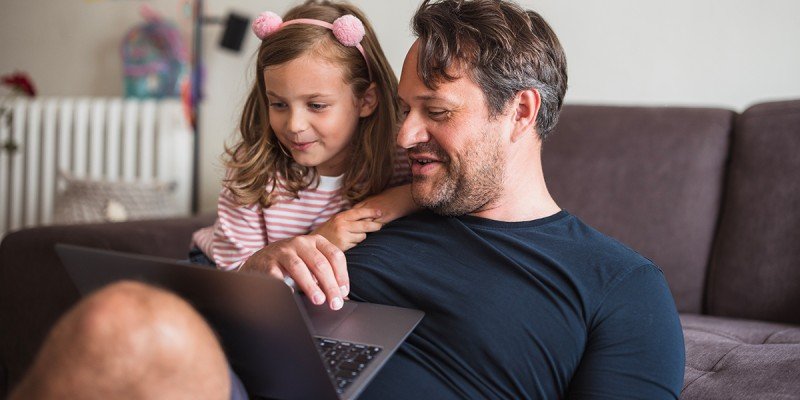 Dad and daughter look at the Marsden's Workplace Savings scheme on their laptop at home.
