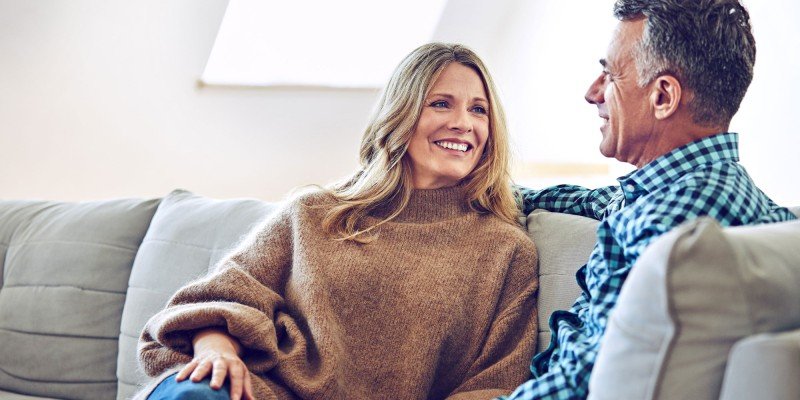 Happy couple sit on sofa after discussing Expat Residential mortgages with Marsden Building Society in Guernsey.