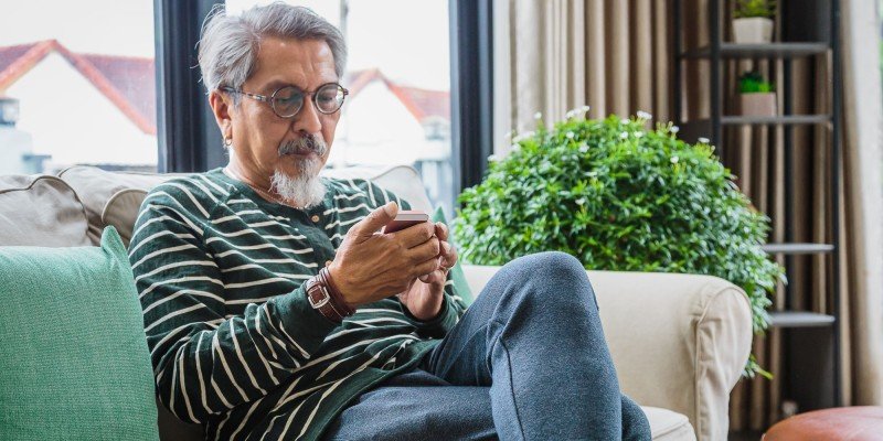 Mature man looks at RIO mortgage rates with Marsden Building Society in Guernsey on his phone.