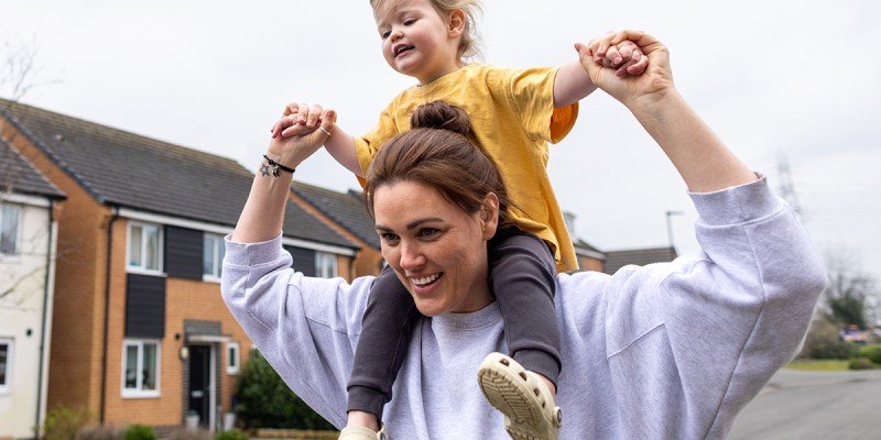 Mum takes a walk with her toddler on her shoulders, reassured that she's building her savings with a Workplace Savings scheme