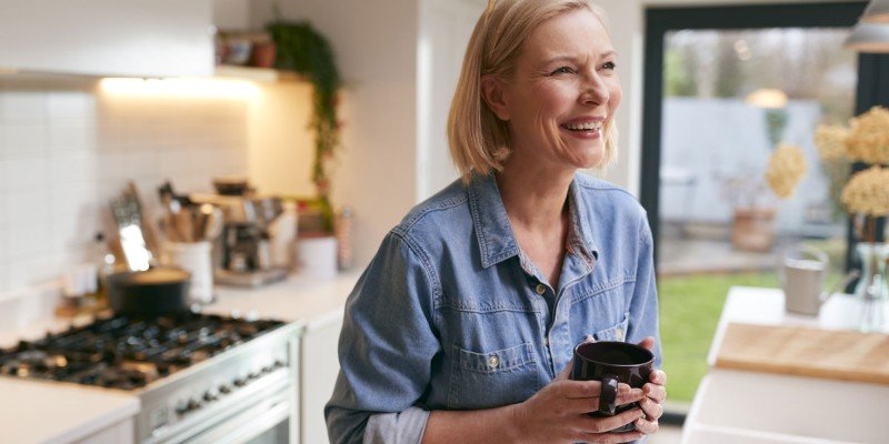 Mature woman smiles in her kitchen after applying for a mortgage with the Marsden in Guernsey.