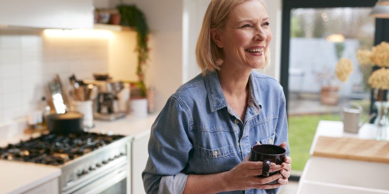 Mature woman smiles in her kitchen after applying for a mortgage with the Marsden in Guernsey.